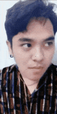 a close up of a man 's face with a plaid shirt