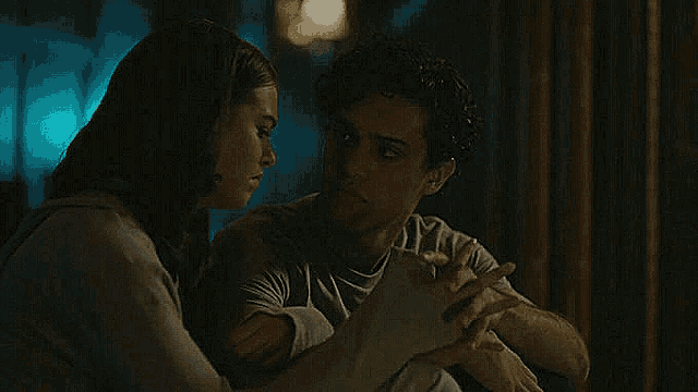 a man and a woman are sitting next to each other in a dark room holding hands .