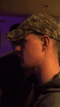 a man wearing a camo hat looks to his right