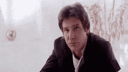 a man in a suit is sitting in front of a white wall .