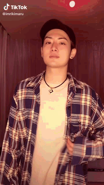 a man wearing a plaid shirt and a hat has a tiktok sticker on his face