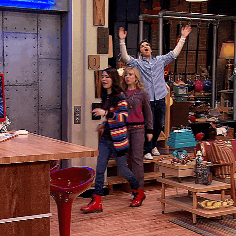 a man and two women are standing in a room with their arms up in the air