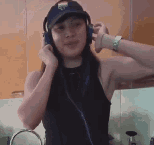 a woman wearing headphones and a hat is standing in front of a kitchen sink
