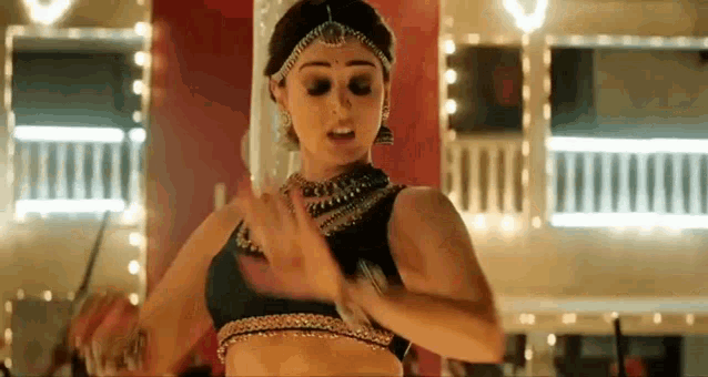 a woman in a black top is dancing in a room with lights on .