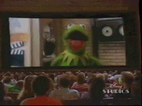 a group of people sitting in front of a screen with studios written on it