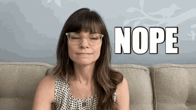 a woman wearing glasses is sitting on a couch with the word nope above her head