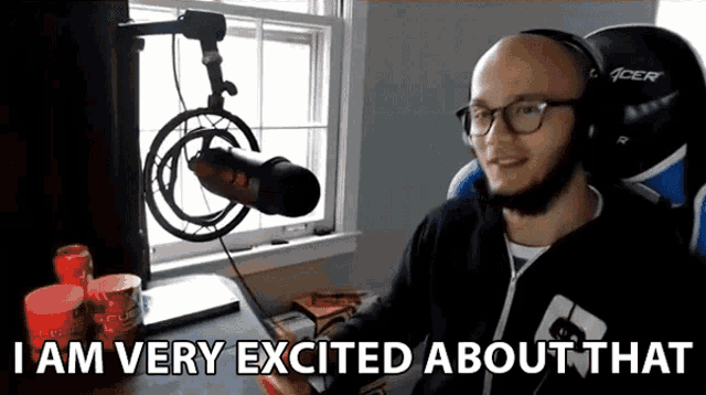 a man sitting in front of a microphone with the words " i am very excited about that " above him