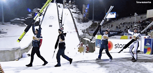 a group of skiers are walking down a snowy slope with a sign that says stop on it