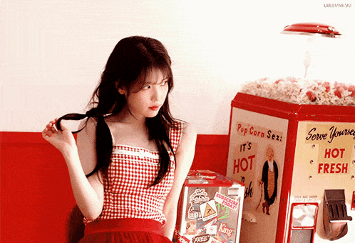 a woman stands in front of a popcorn machine that says it 's hot and fresh
