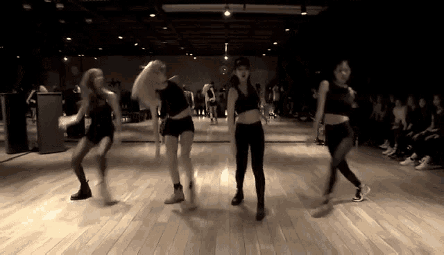 a group of women are dancing in a dance studio in front of a crowd .