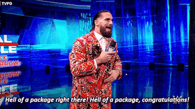 a man in a suit is talking into a microphone and says hell of a package right there