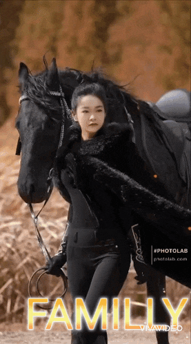 a woman is standing next to a black horse with the word family in the corner
