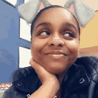 a woman wearing a cat ear filter is smiling and looking at the camera .