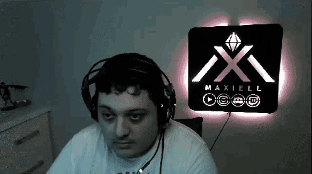 a man wearing headphones is sitting in front of a maxell sign