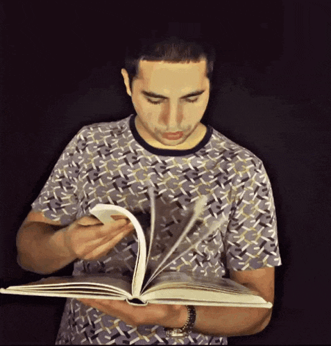 a man in a patterned shirt is reading a large book