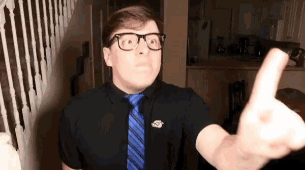 a man in a black shirt and blue tie is giving a thumbs up .