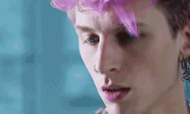 a close up of a man with pink hair and earrings