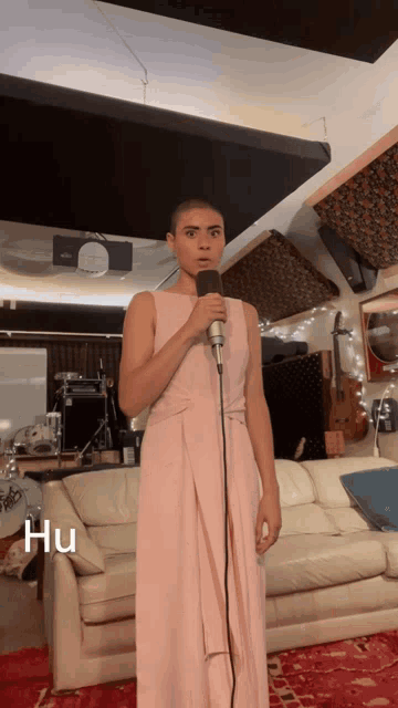 a woman in a pink dress is singing into a microphone and the word hu is on the bottom