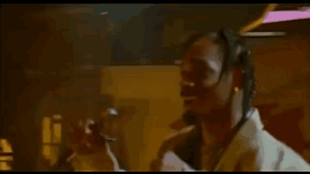 a man with dreadlocks is smoking a cigarette in a room .