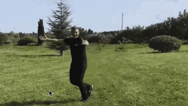a man is standing in the grass with his arms outstretched in a park .
