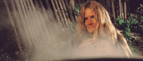 a woman with long blonde hair is sitting in a bath tub