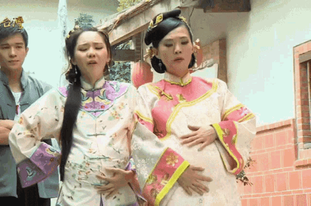 a pregnant woman holds her belly while a man looks on