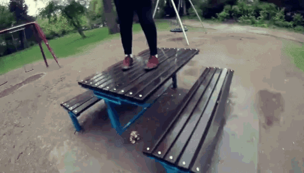 a person is standing on a wooden picnic table
