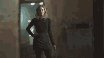 a woman is standing in a dark room with her hands on her hips