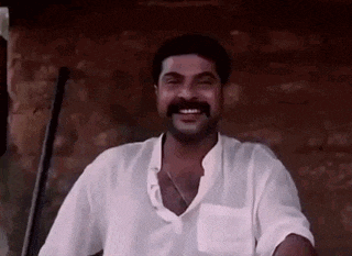 a man with a mustache is smiling and holding a sword in his hand .