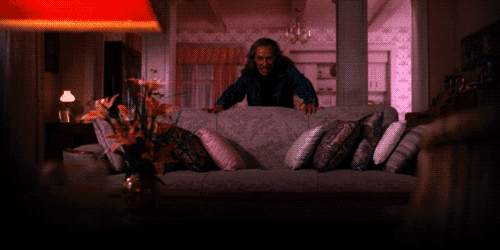 a man sitting on a couch in a living room with a lamp in the background