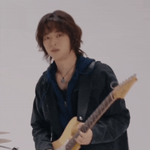 a young man is playing a guitar in a band .