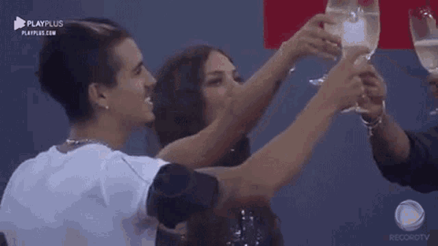 a man and a woman are toasting with wine glasses while standing next to each other .