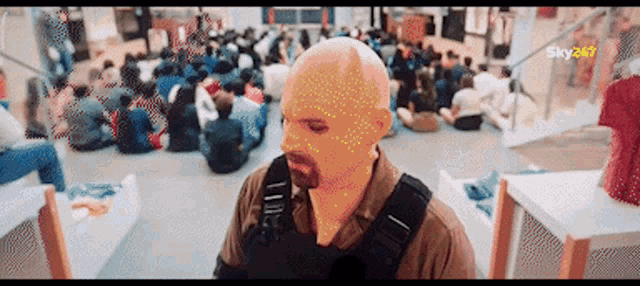 a man wearing a mask stands in front of a crowd of people with sky247 written in the corner