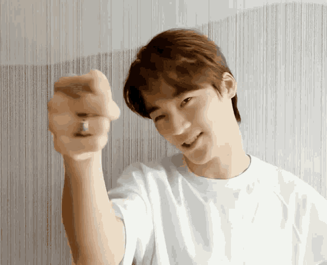 a man wearing a white shirt and a ring on his finger is pointing at the camera