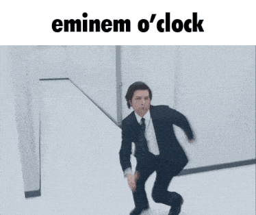 a man in a suit and tie is running in a hallway with the caption eminem o ' clock