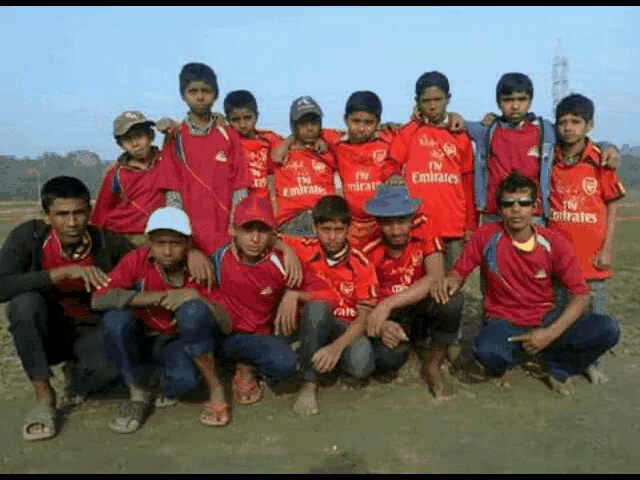 a group of boys wearing red emirates jerseys pose for a picture