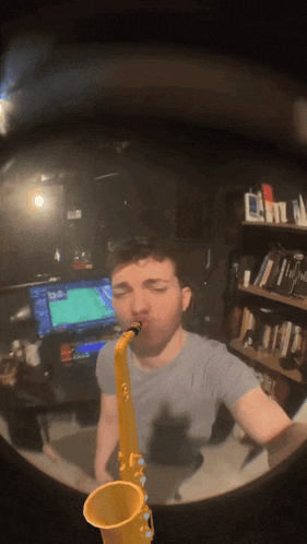 a man plays a saxophone in front of a computer monitor