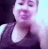 a woman in a purple tank top is making a funny face with her hand .