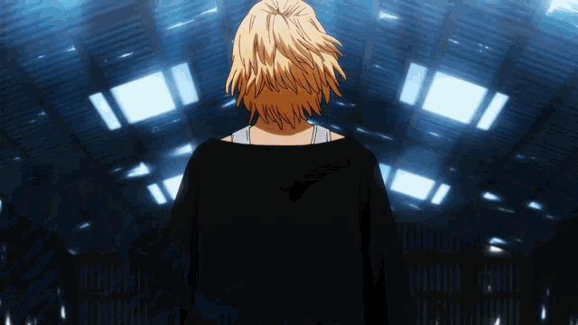 a person in a black shirt stands in front of a blue background