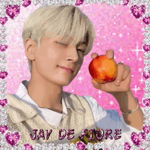 a young man is holding an apple in his hand in front of a pink background with the name jay de fiore written on it .
