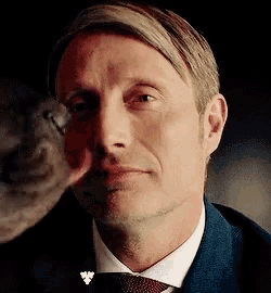 a close up of a man in a suit and tie looking at a bird .