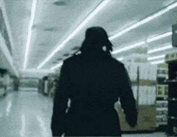 a blurred image of a person walking through a store with a sign that says ' i ' on it