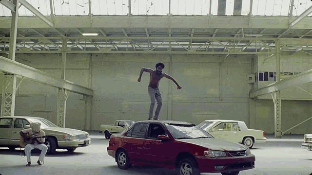 a man stands on top of a red car