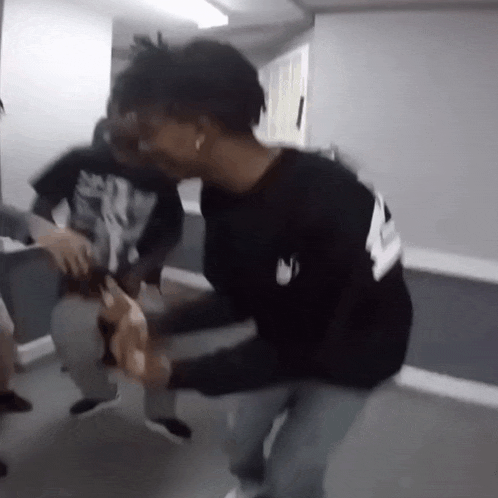 a man in a black shirt is kneeling down next to another man in a white shirt .