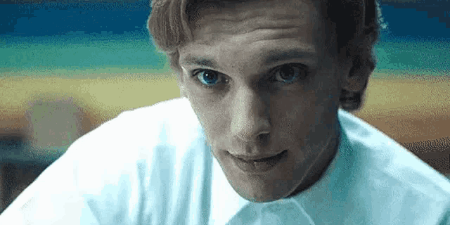 a close up of a man 's face with a white shirt on .