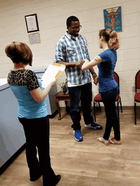 a woman in a blue shirt is standing next to a man in a plaid shirt and a girl in a blue shirt