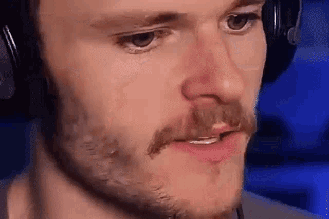 a close up of a man with a beard wearing headphones and making a funny face .