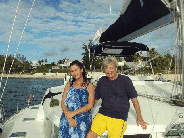 a man and a woman are posing for a picture on the deck of a sailboat
