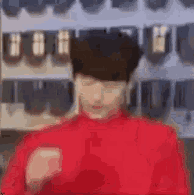 a blurry picture of a man in a red sweater making a funny face .