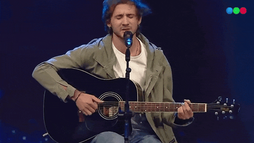 a man playing a guitar and singing into a microphone